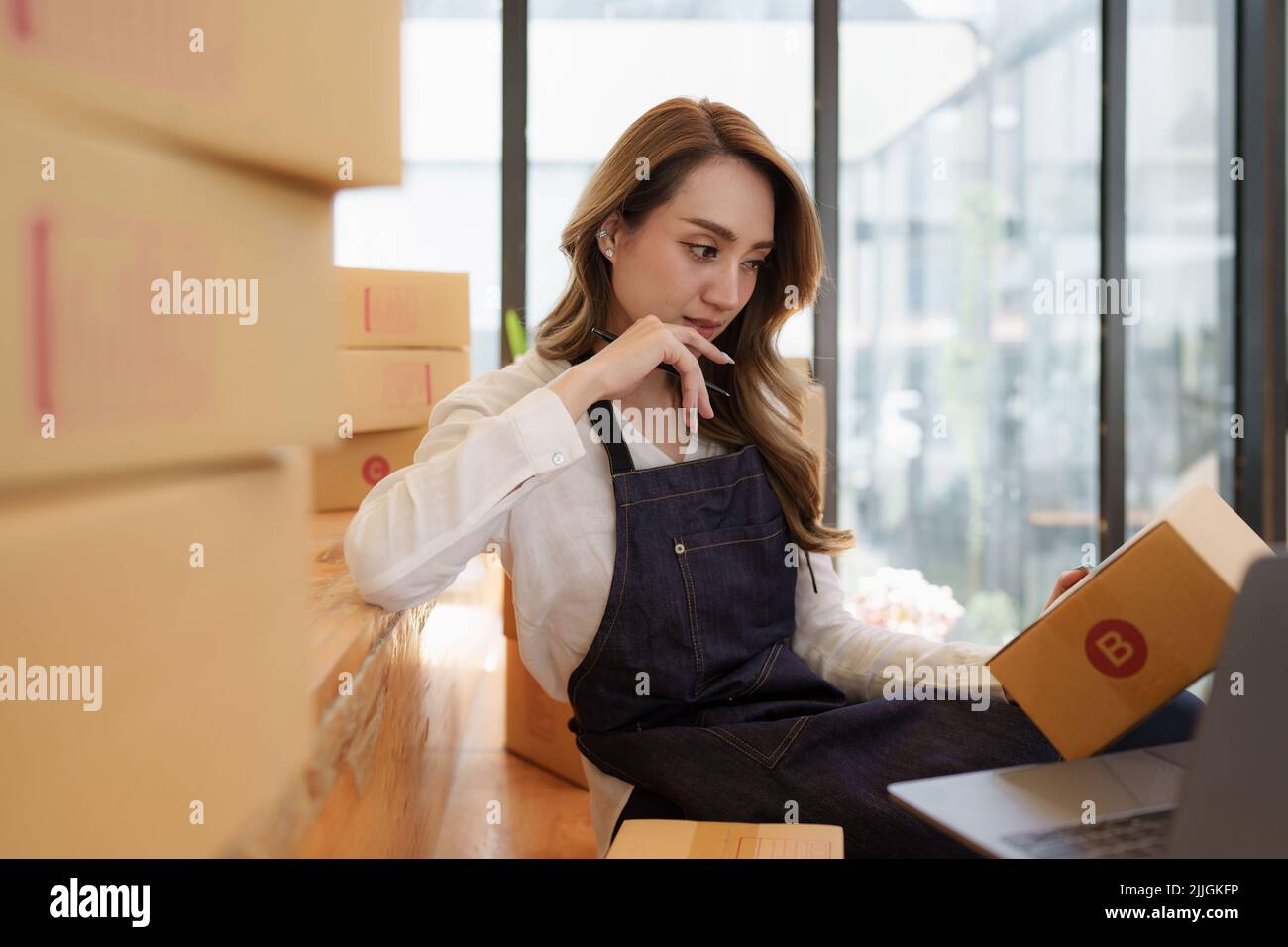 Giovane donna asiatica in magazzino per la consegna al proprietario imprenditore PMI. Business digitale online PMI piccole imprese e negozio online. Foto Stock