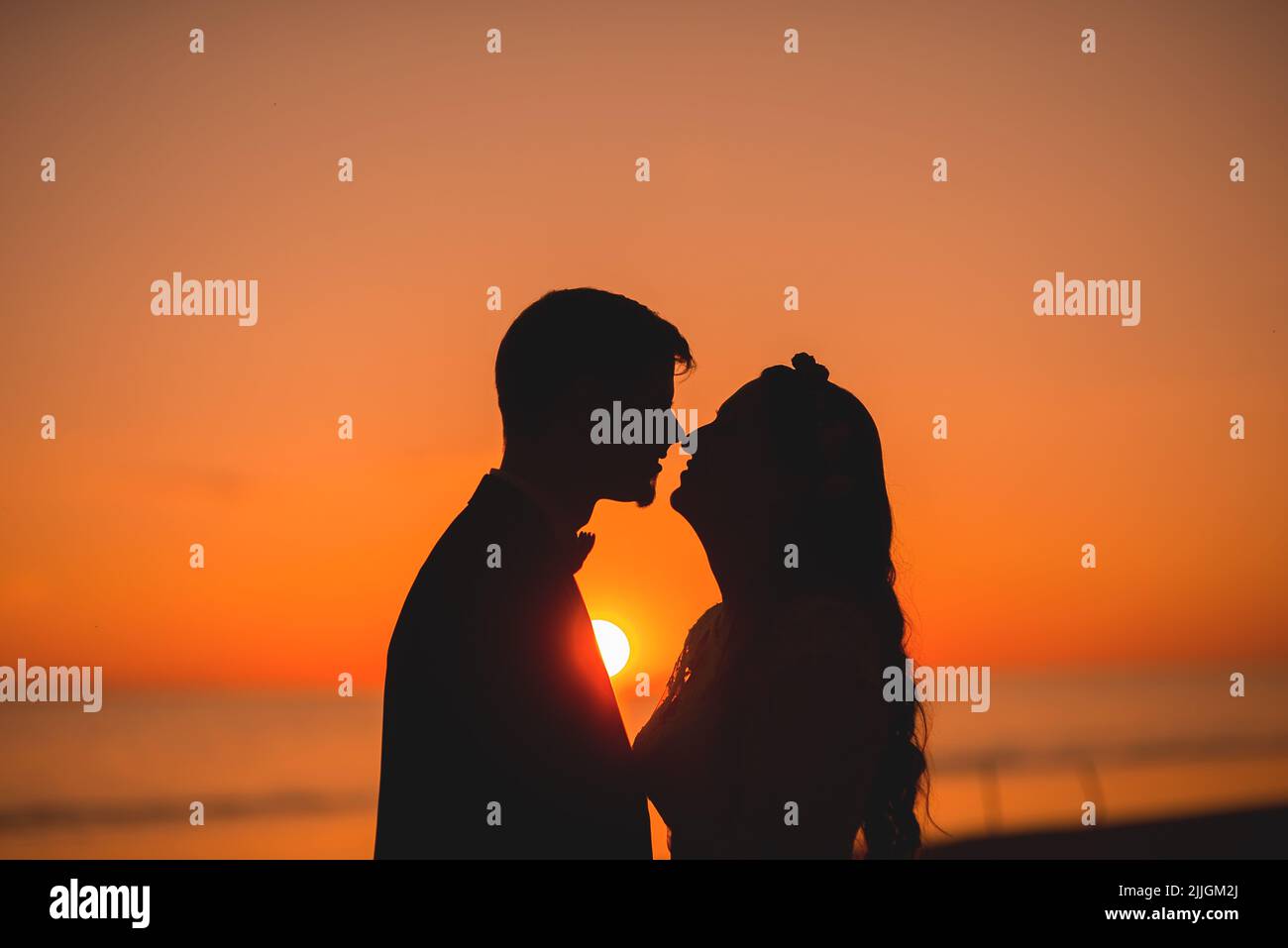 La silhouette ravvicinata della coppia che si bacia sulla riva al tramonto Foto Stock