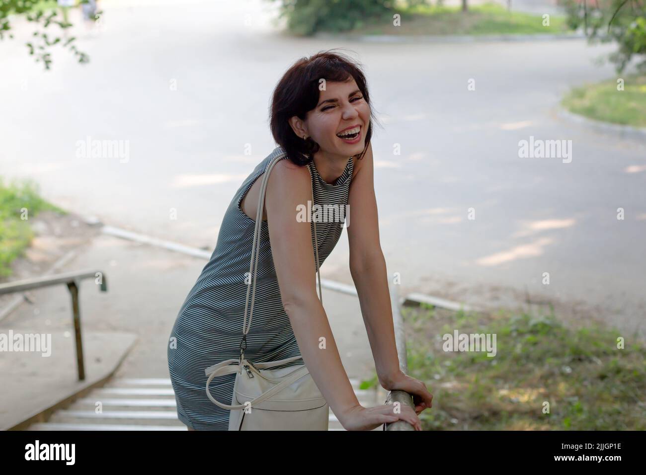 Una donna allegra rotola con risate dopo aver sentito uno scherzo da un amico. Foto Stock