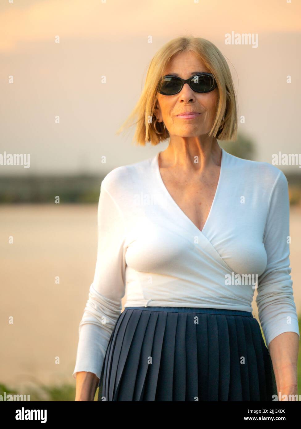 senior fit elegante donna vestita blaka dn bianco indossare occhiali da sole godere della natura in estate Foto Stock