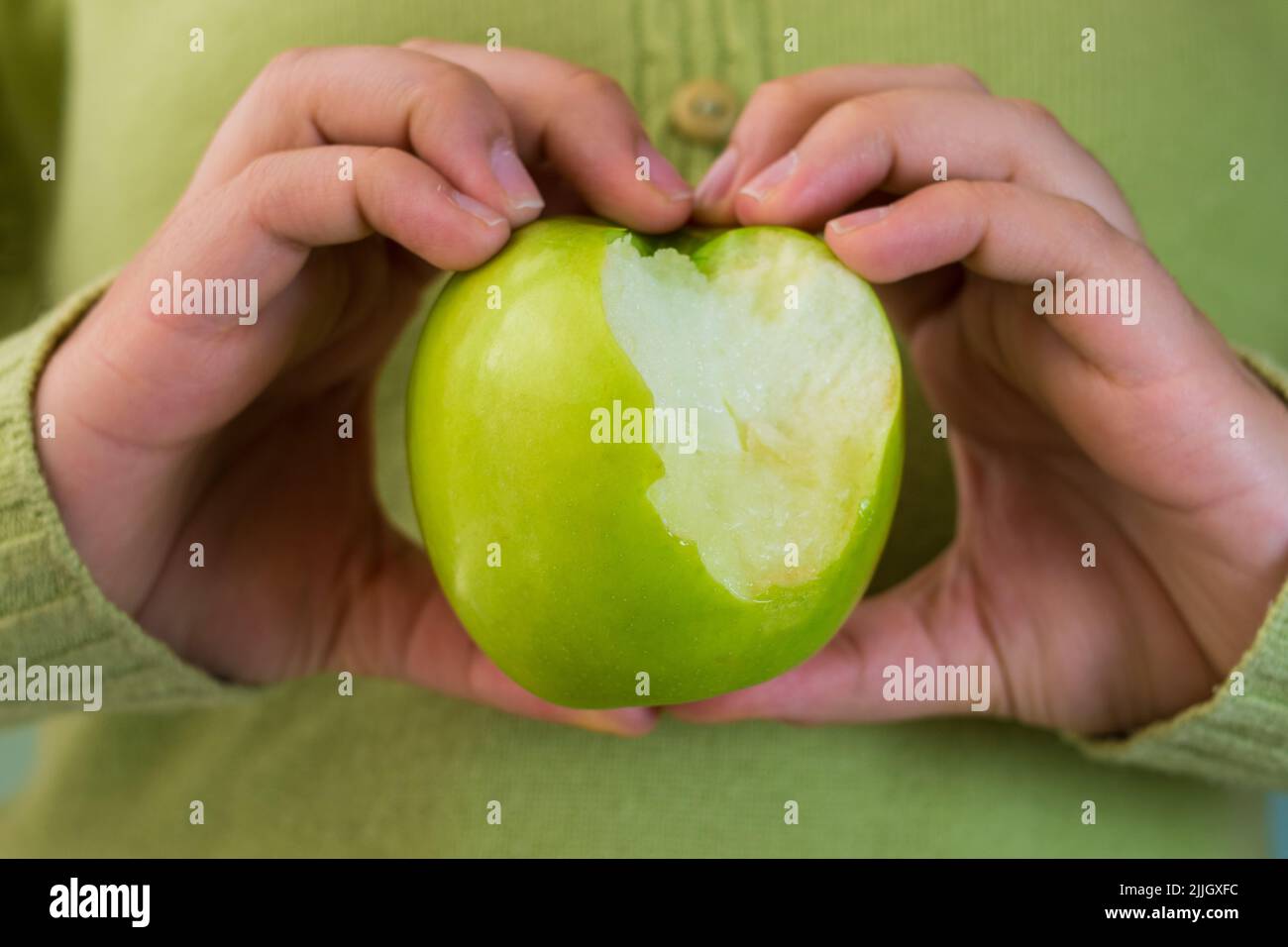 Una mano che tiene una mela verde morso Foto Stock
