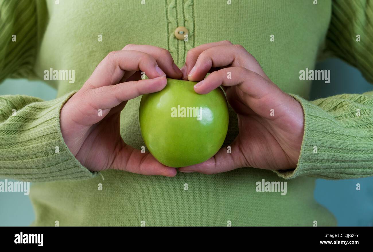 Una mano che tiene una mela verde Foto Stock