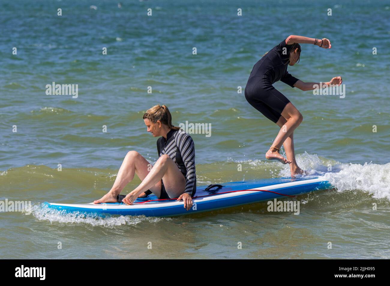 Standup paddleboarding, due ragazze malate che praticano per mantenere il loro equilibrio su paddleboard / SUP board in mare Foto Stock