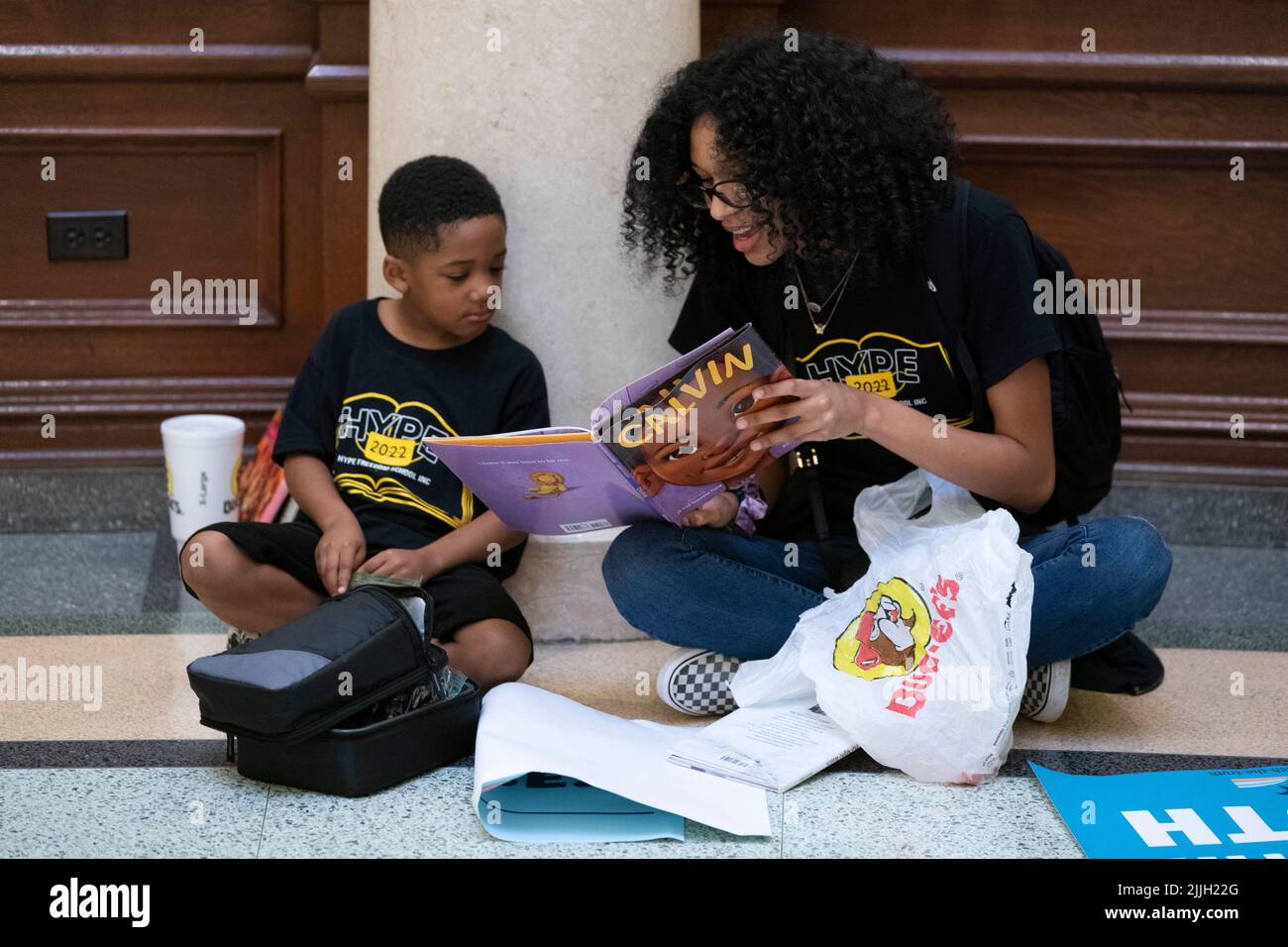 Austin Texas USA, luglio 26 2022: SUMMER WILLIAMS of Houston legge il libro per bambini 'Calvin' all'amico T.J. SALA. La coppia si è unita ad altri attivisti protestando contro la censura dei libri nelle aule scolastiche pubbliche e nelle biblioteche. I manifestanti si sono seduti nella rotonda del Campidoglio e hanno letto alcuni dei 850 libri elencati nella lista dei titoli 'scomodi' di un legislatore repubblicano. Credit: Bob Daemmrich/Alamy Live News Foto Stock