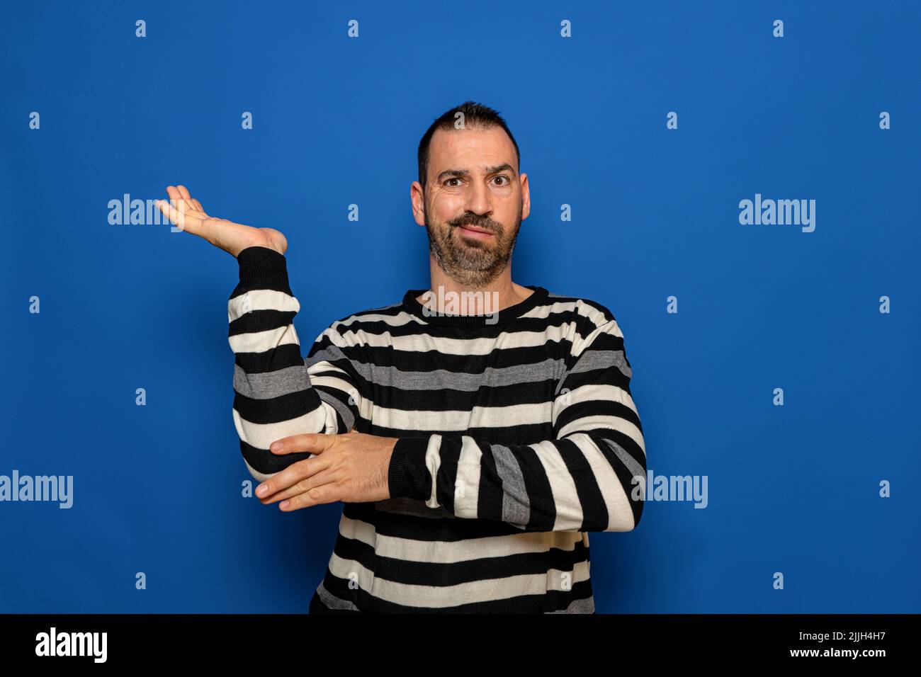 Bell'uomo caucasico che tiene un immaginario spazio di copia sul palmo della sua mano per inserire un annuncio su sfondo blu isolato. Foto Stock