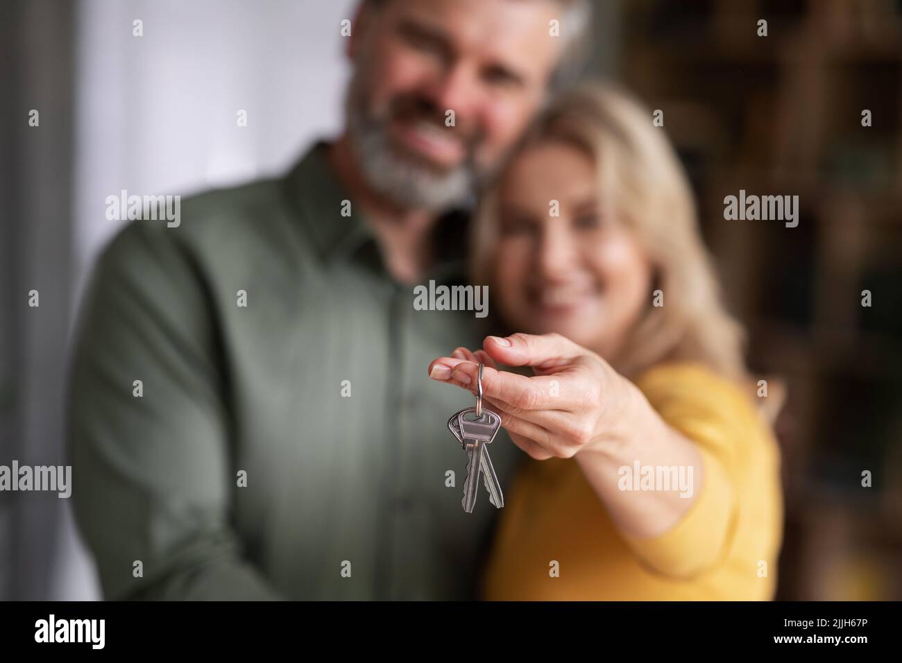 Casa di famiglia. Buone sposi di mezza età che posano con le chiavi domestiche nelle mani Foto Stock