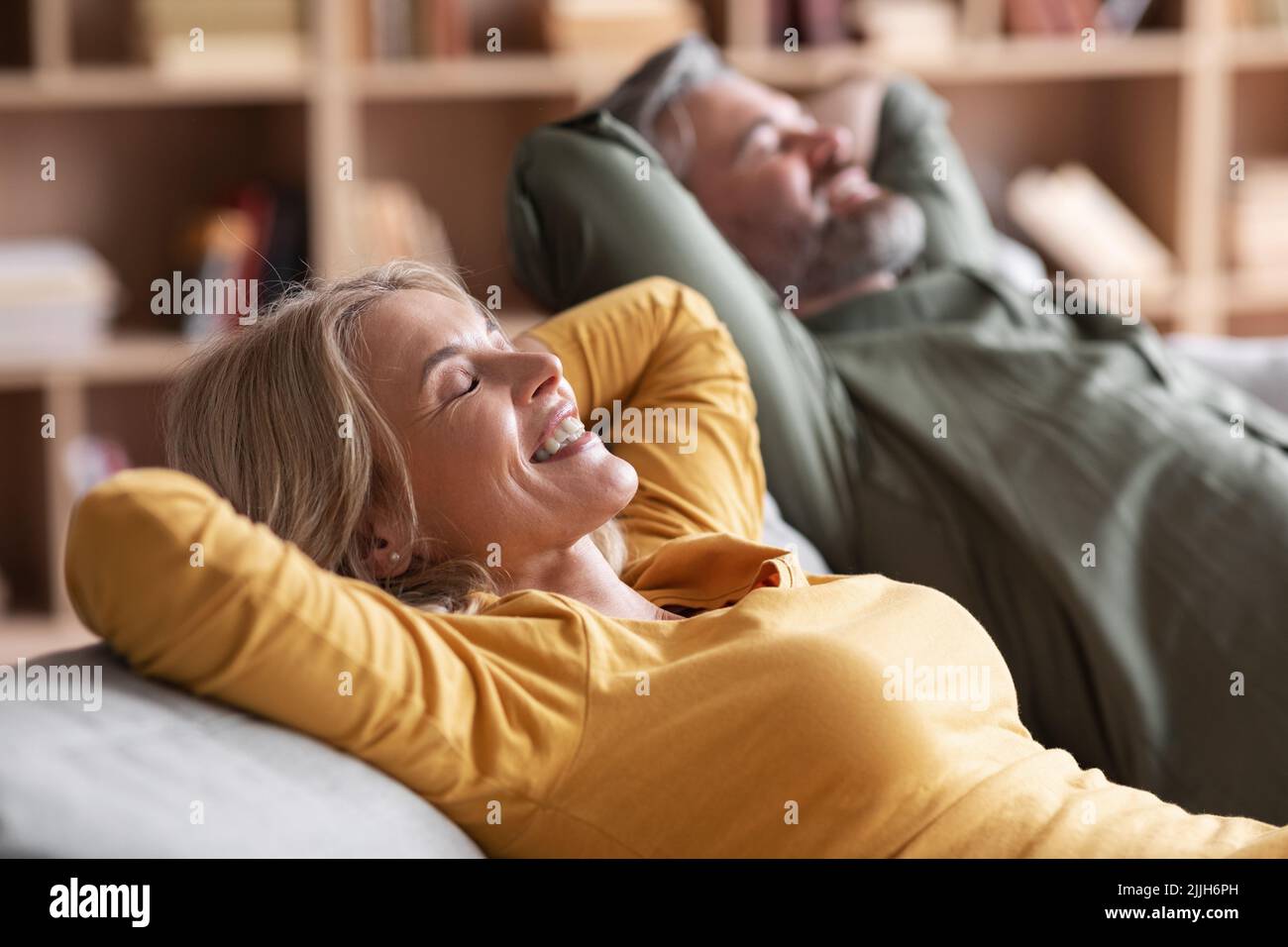 Felicemente rilassato sposi di mezza età appoggiarsi sul comodo divano Foto Stock