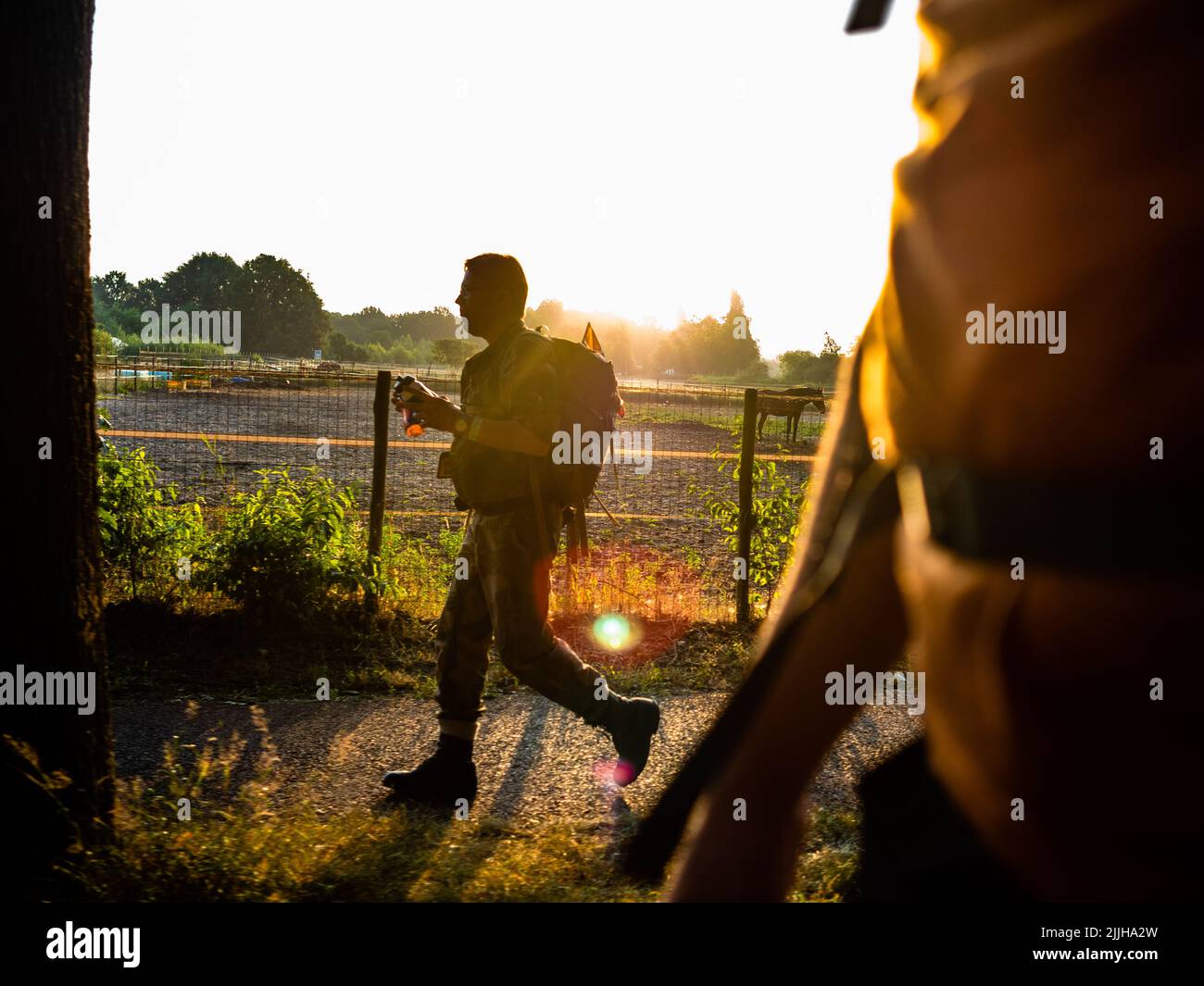 Un uomo cammina mentre il sole sorge durante il più grande evento a piedi di più giorni del mondo. La marcia dei quattro giorni (in olandese 'Vierdaagse') è vista come il primo esempio di sportività e di legame internazionale tra militari e civili di molti paesi diversi. Dopo due anni di cancellazioni, si è tenuto di nuovo, ma il primo giorno è stato annullato a causa delle temperature calde, trasformando le quattro marce in tre giorni marce. Questa è l'edizione del 104 e il totale ufficiale degli escursionisti registrati è stato di 38.455 provenienti da 69 paesi. Possono scegliere di camminare 30km, 40km o 50km al giorno. (Foto di Ana Fern Foto Stock