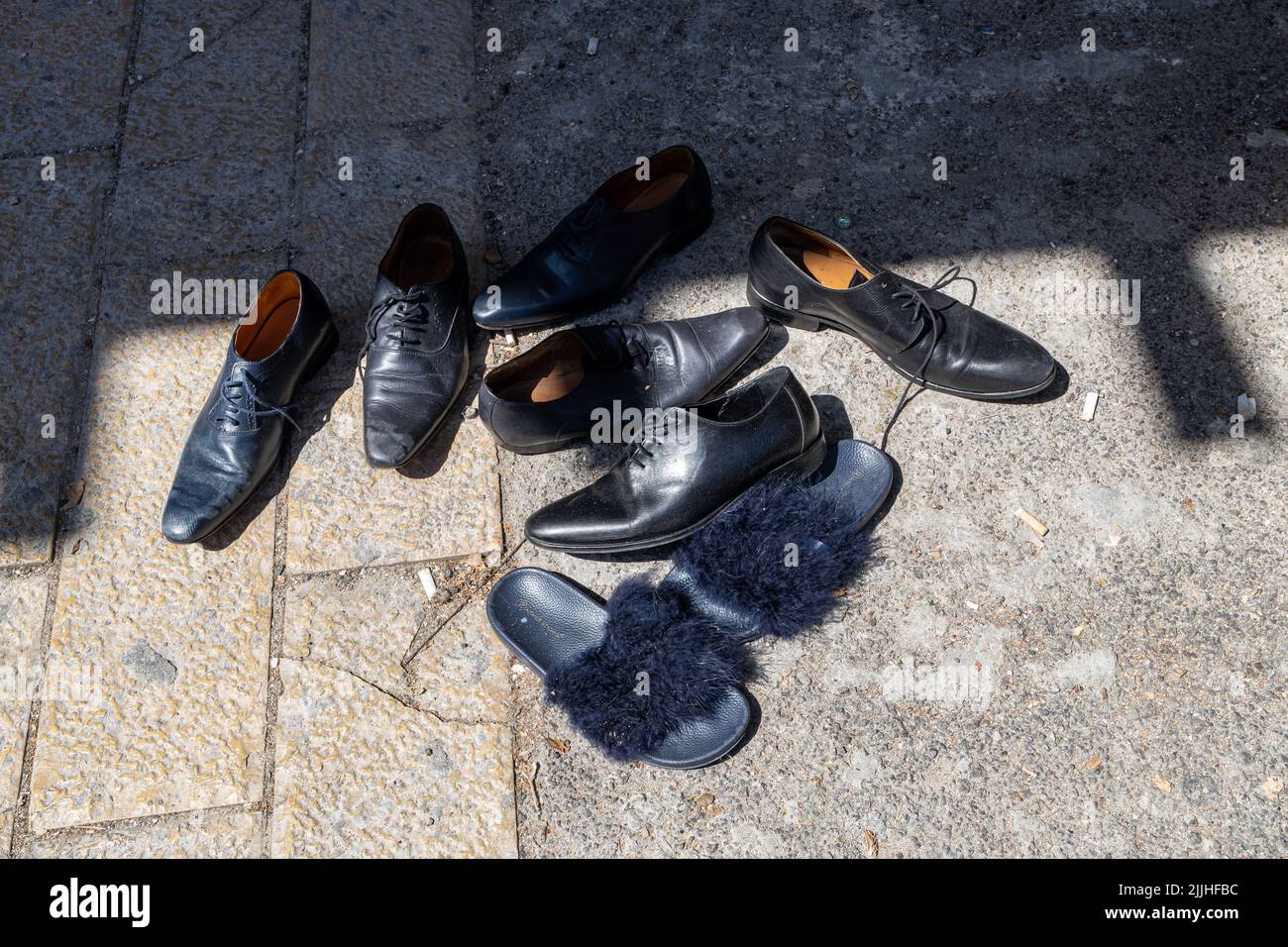 Haifa, Israele - 20 luglio 2022, scena del mercato delle pulci, con venditori e acquirenti, in centro. Molte scarpe in pelle verniciata nera sul marciapiede Foto Stock