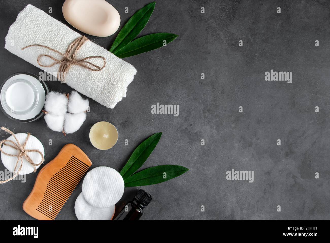 Cosmetici naturali per la cura del corpo su sfondo concreto. Accessori per il centro benessere, asciugamano, spazzola per capelli, olio essenziale. Composizione della disposizione piatta. Prodotti ecologici, Zer Foto Stock