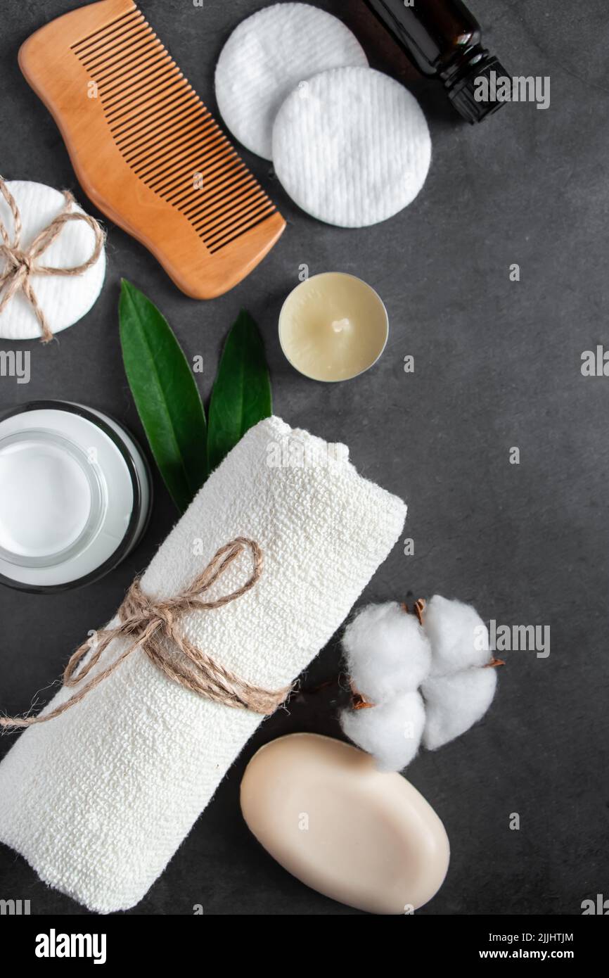 Cosmetici naturali per la cura del corpo su sfondo concreto. Accessori per il centro benessere, asciugamano, spazzola per capelli, olio essenziale. Composizione della disposizione piatta. Prodotti ecologici, Zer Foto Stock