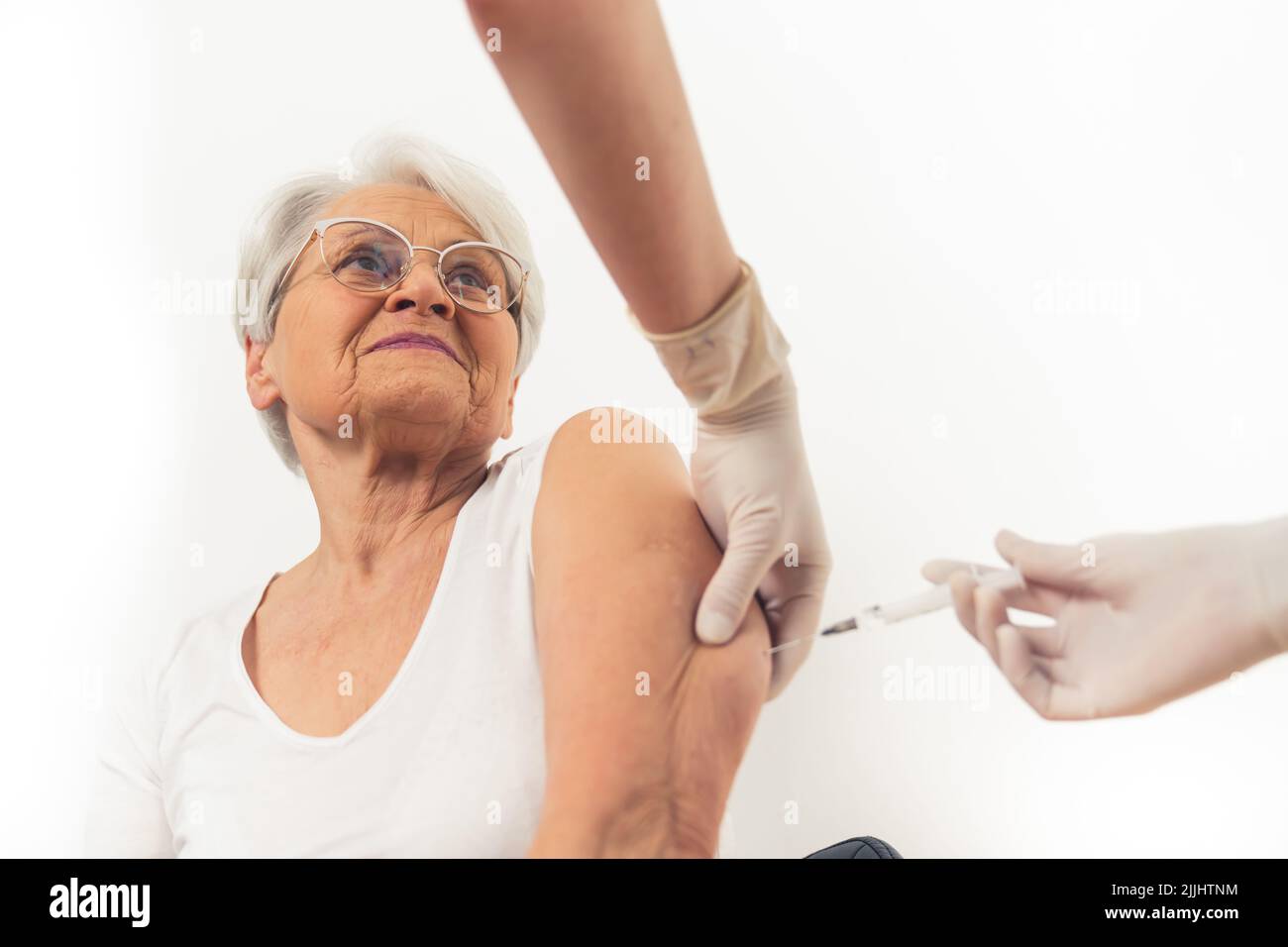 Una vecchia donna felicissima dai capelli grigi che riceve un vaccino per proteggersi dal virus. Foto di alta qualità Foto Stock