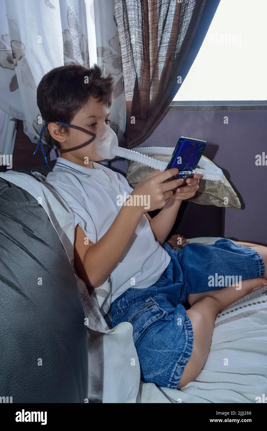 Bambino con maschera di appannamento sul suo viso gioco. Salvador, Bahia, Brasile. Foto Stock