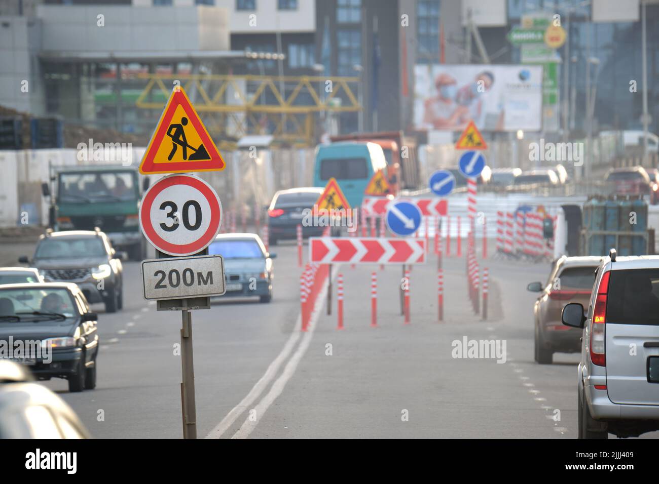 Lavori stradali che avvertono segnali stradali di lavori di costruzione su strade urbane e auto in movimento lento Foto Stock