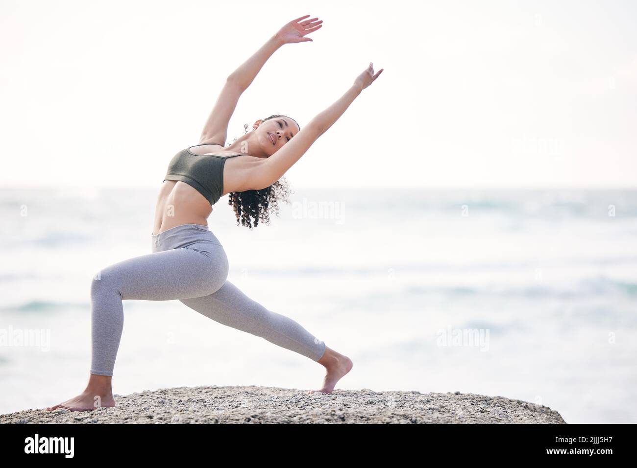 Lo yoga vi permette di trovare un nuovo tipo di libertà. Una giovane donna che pratica lo yoga sulla spiaggia. Foto Stock