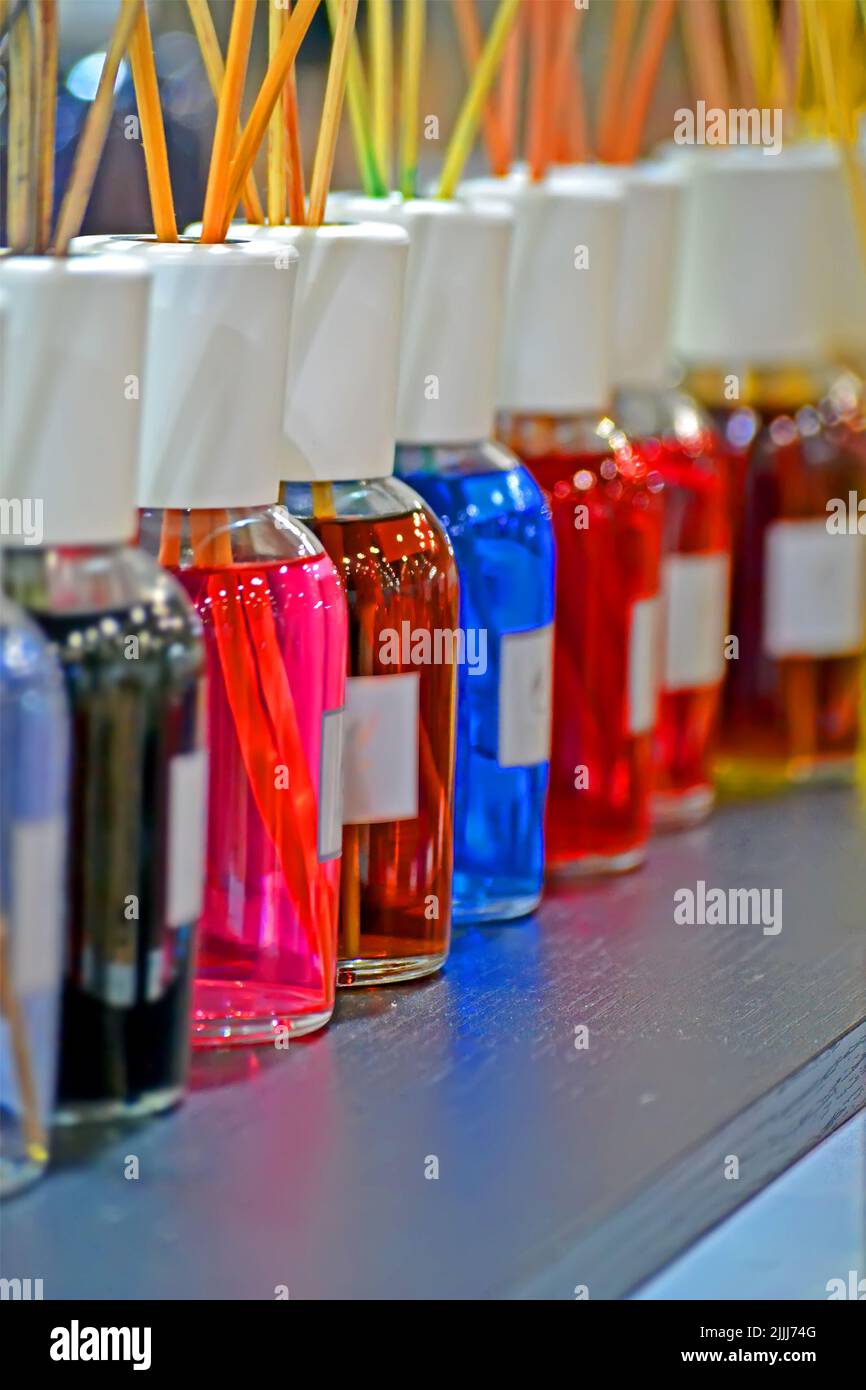 le bottiglie cosmetiche astratte dell'arcobaleno si allineano sul tavolo di legno con i bastoncini heap, la diversità di colore dell'aroma Foto Stock