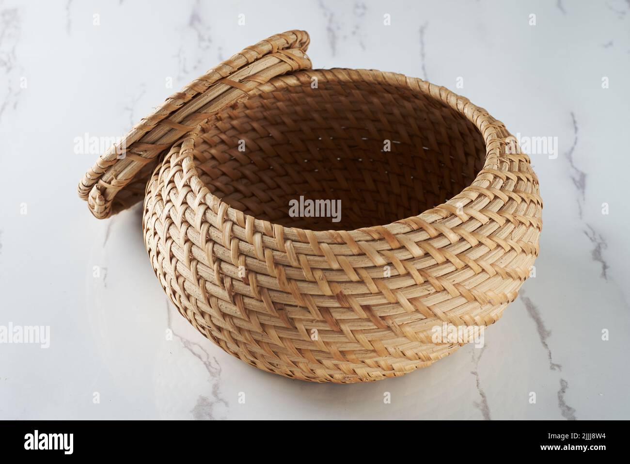 Un artigianato sotto forma di un contenitore di stoccaggio con un coperchio in rattan intrecciato Foto Stock