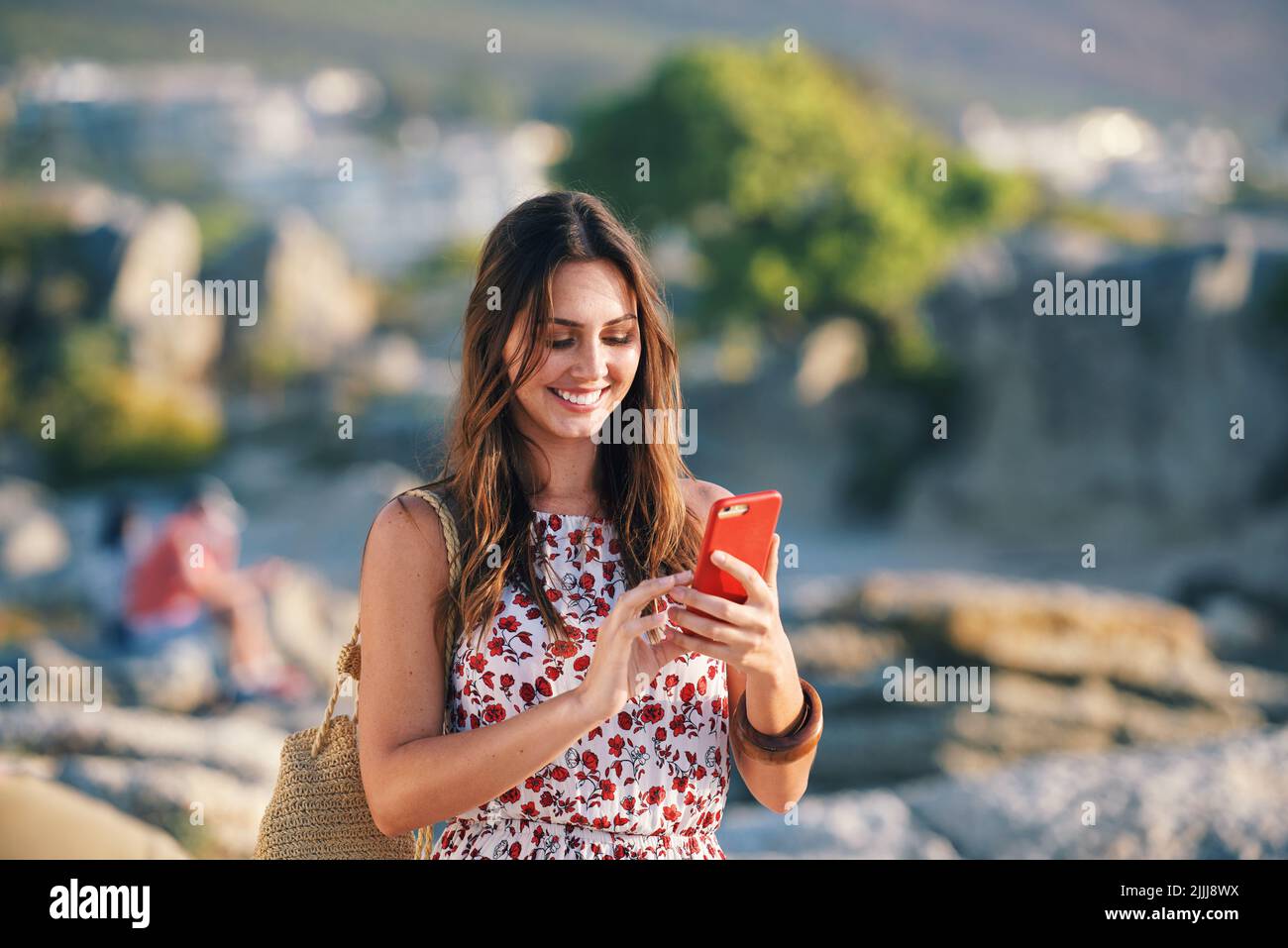 Bella donna con smartphone SMS sulla spiaggia al tramonto Foto Stock