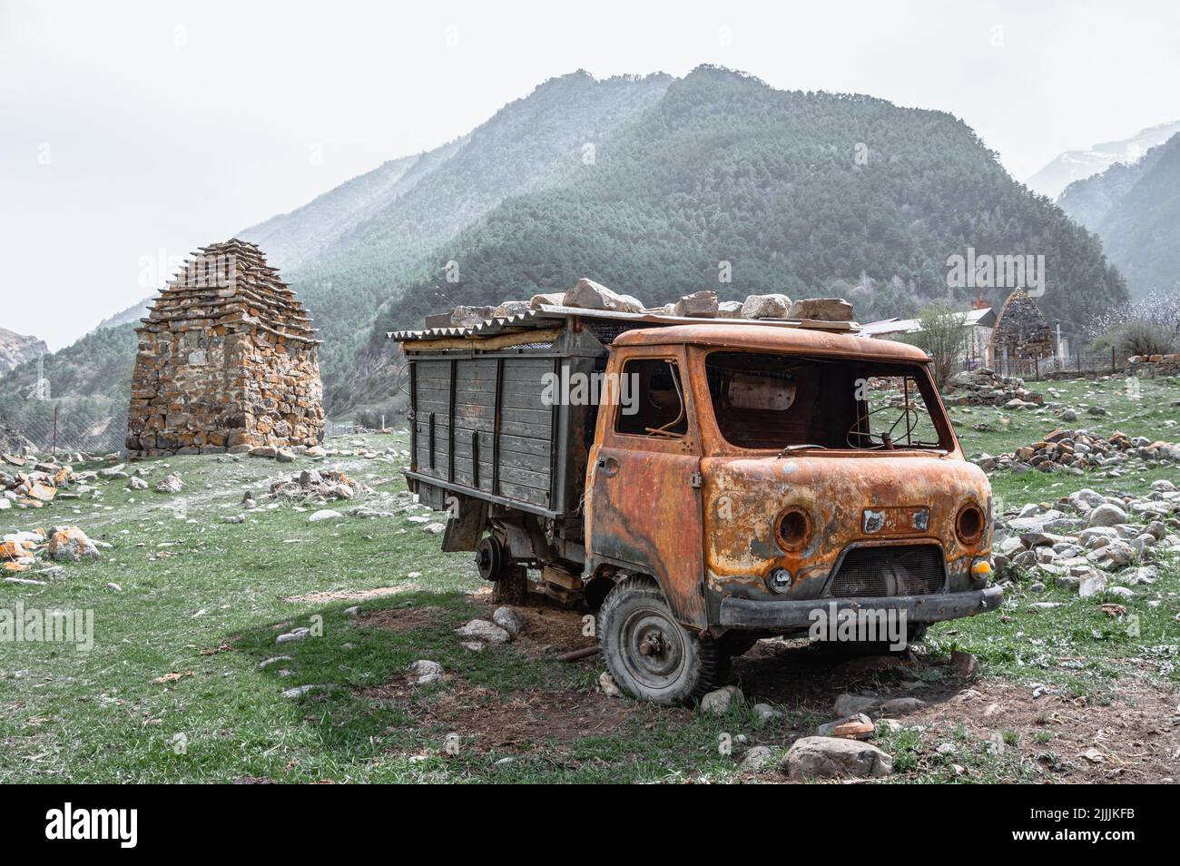 Arrugginito camion sovietico in mezzo al villaggio desolato contro cielo nebbia. Digoria, Ossezia settentrionale. Foto Stock