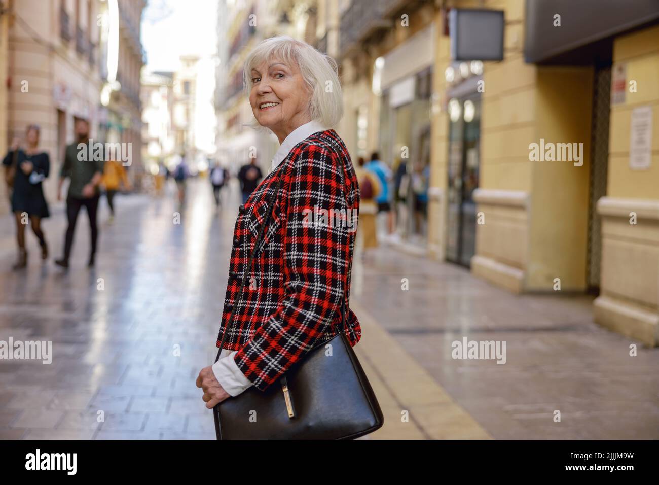 Donna pensionato alla moda che cammina all'aperto in città Foto Stock