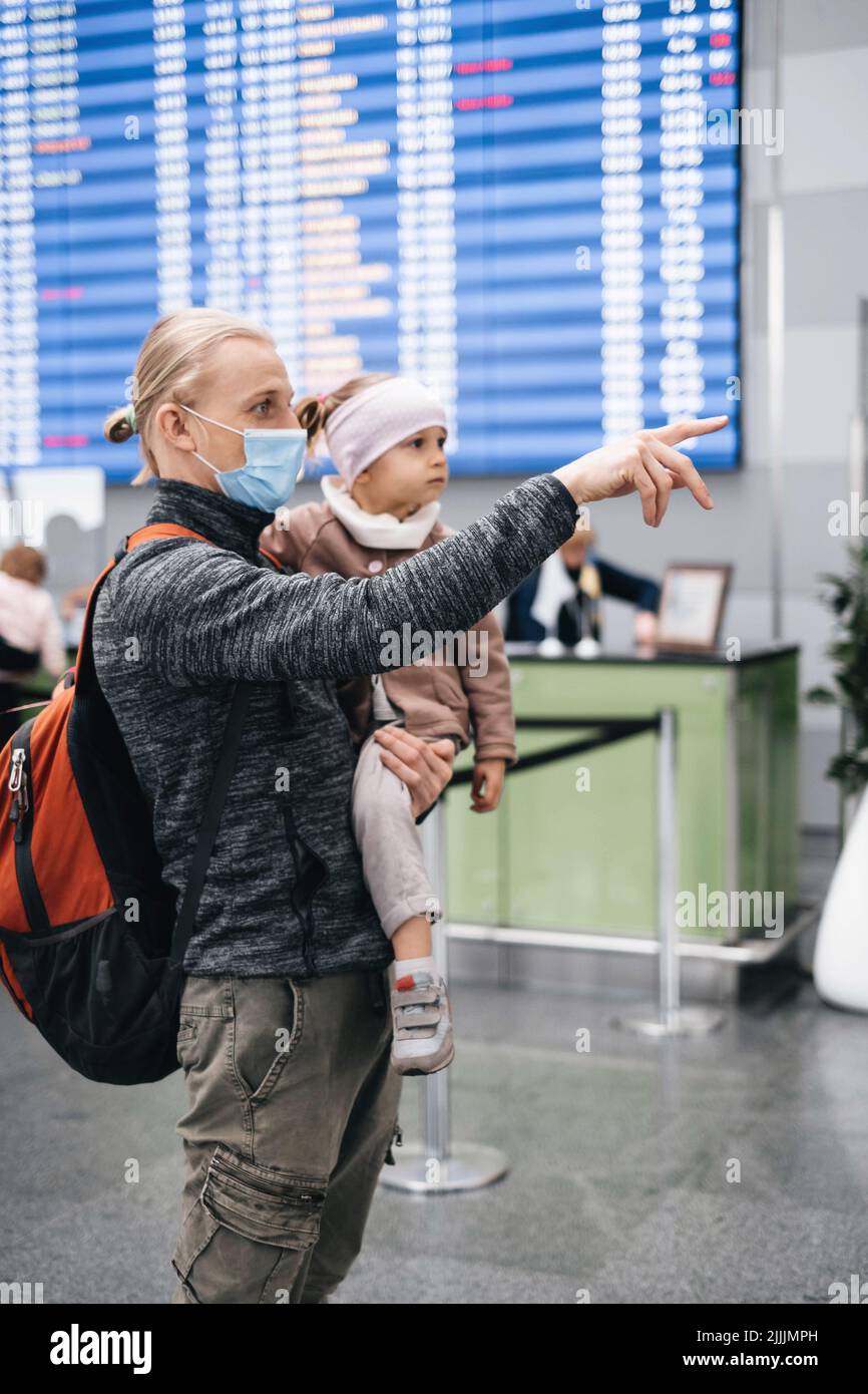 Uomo e ragazza che guardano le informazioni degli orari in aeroporto, passeggeri in attesa di un aereo. Viaggio in famiglia in aereo. Ritardo del volo Foto Stock