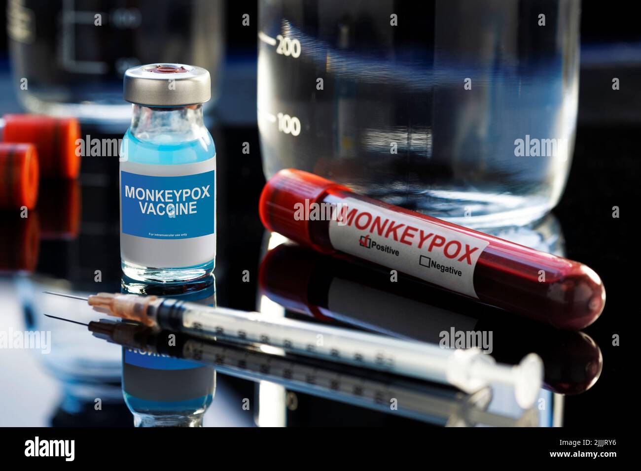 Flacone di vaccino scritto Monkeypox con un liquido blu, una siringa e un campione di sangue su un laboratorio come sfondo. Foto Stock