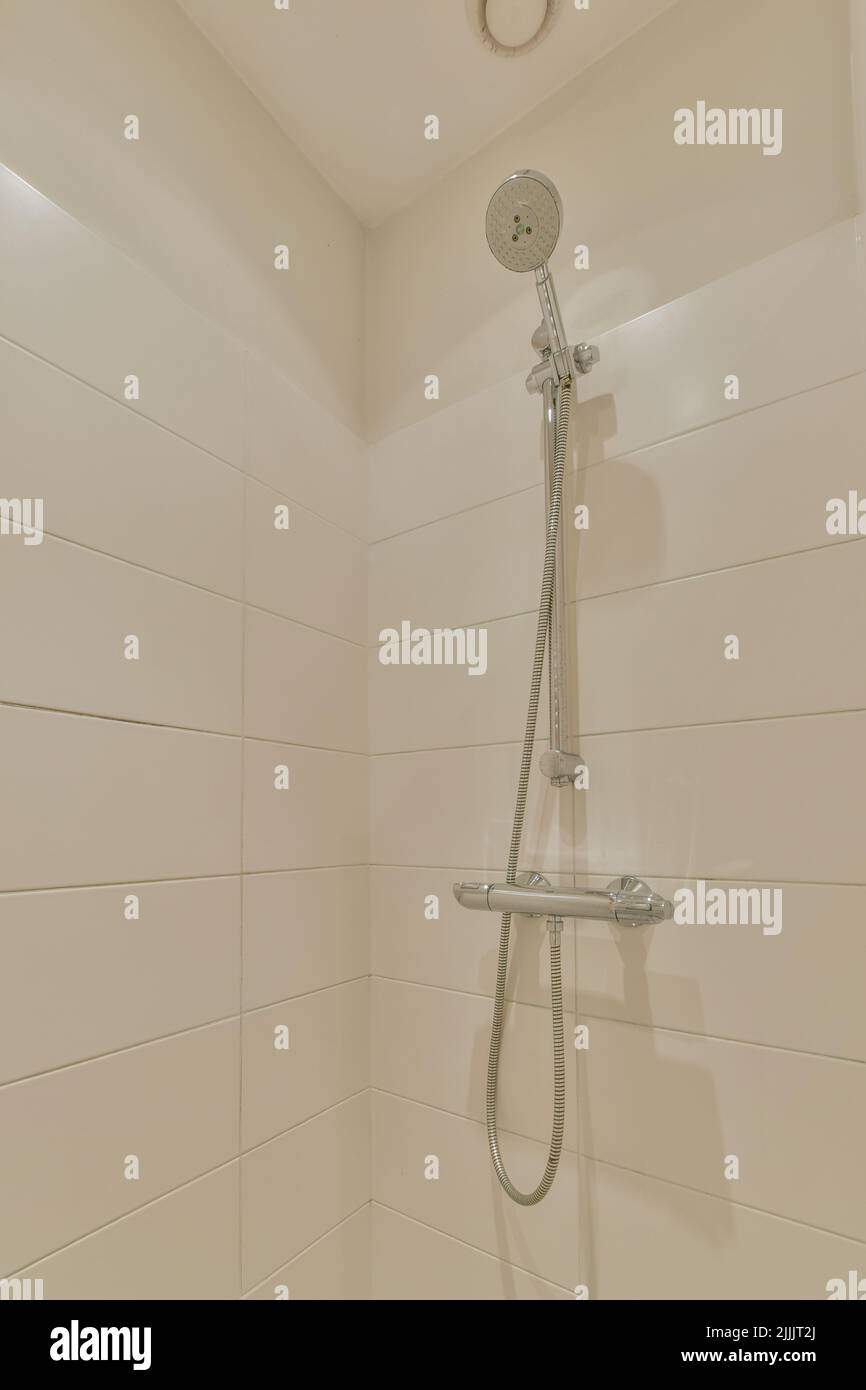 Moderna colonna doccia in un costoso bagno aperto con pareti e finestre in piastrelle grigie Foto Stock