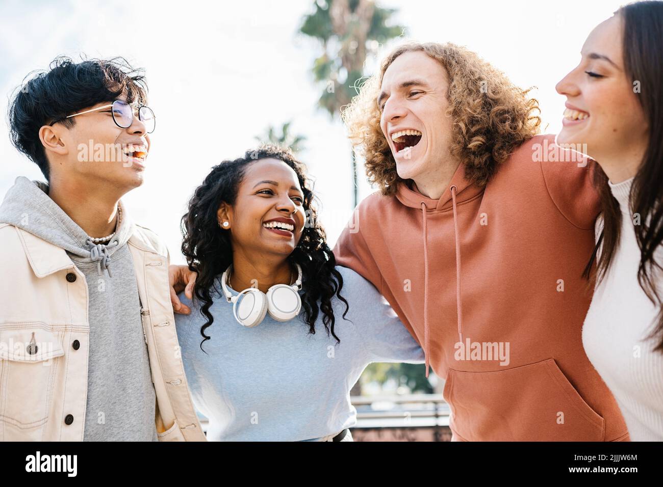 Gruppo felice di giovani amici multirazziali che si divertono abbracciandosi a vicenda Foto Stock