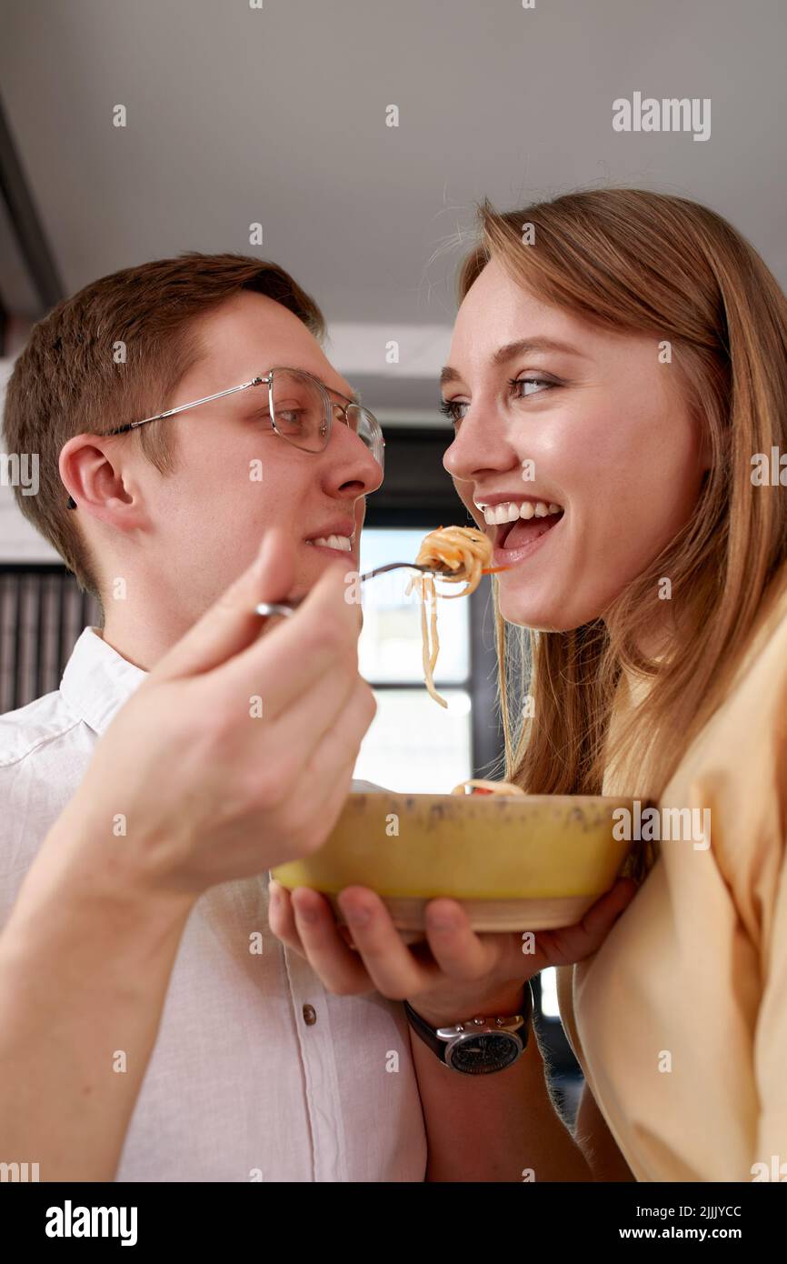 Sorridendo amorevole marito che alimenta moglie, giovane coppia che gode momento tenero, data romantica, divertirsi, mangiare cucina giapponese, felice famiglia spesa Foto Stock