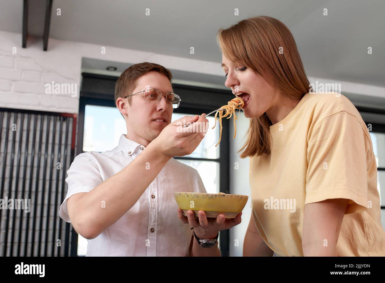 Sorridendo amorevole marito che alimenta moglie, giovane coppia che gode momento tenero, data romantica, divertirsi, mangiare cucina giapponese, felice famiglia spesa Foto Stock