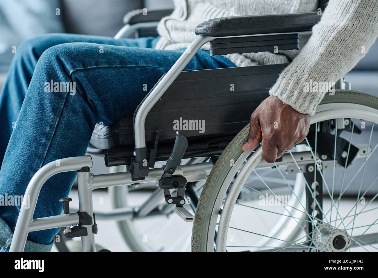 Primo piano di un uomo africano con disabilità che utilizza la sedia a rotelle per muoversi durante la sua riabilitazione Foto Stock
