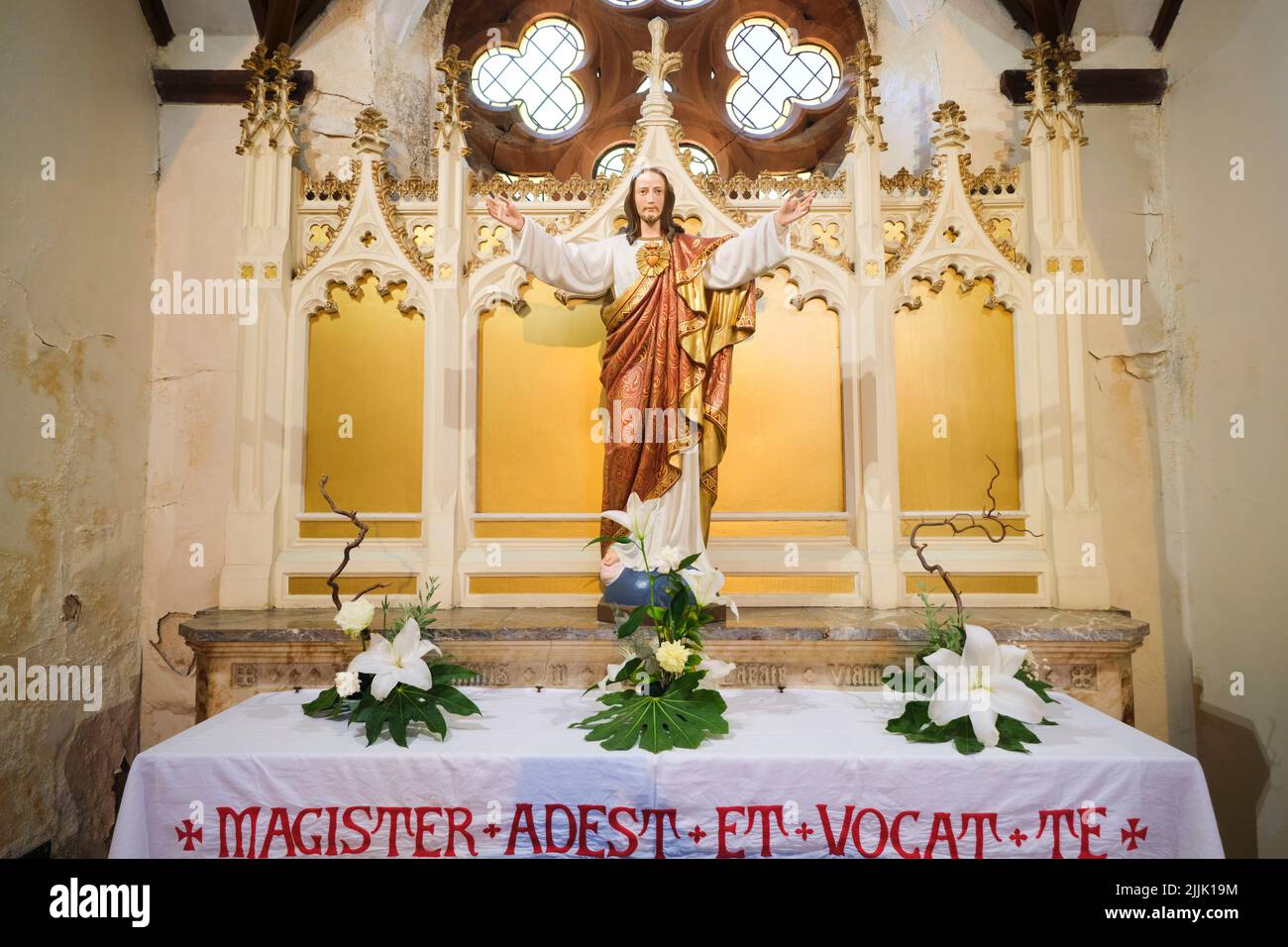 Un altare laterale con una grande statua di Gesù che porta un abito rosso e oro con un cuore sul petto. Alla Cattedrale Metropolitana di Cardiff, Galles, United K Foto Stock