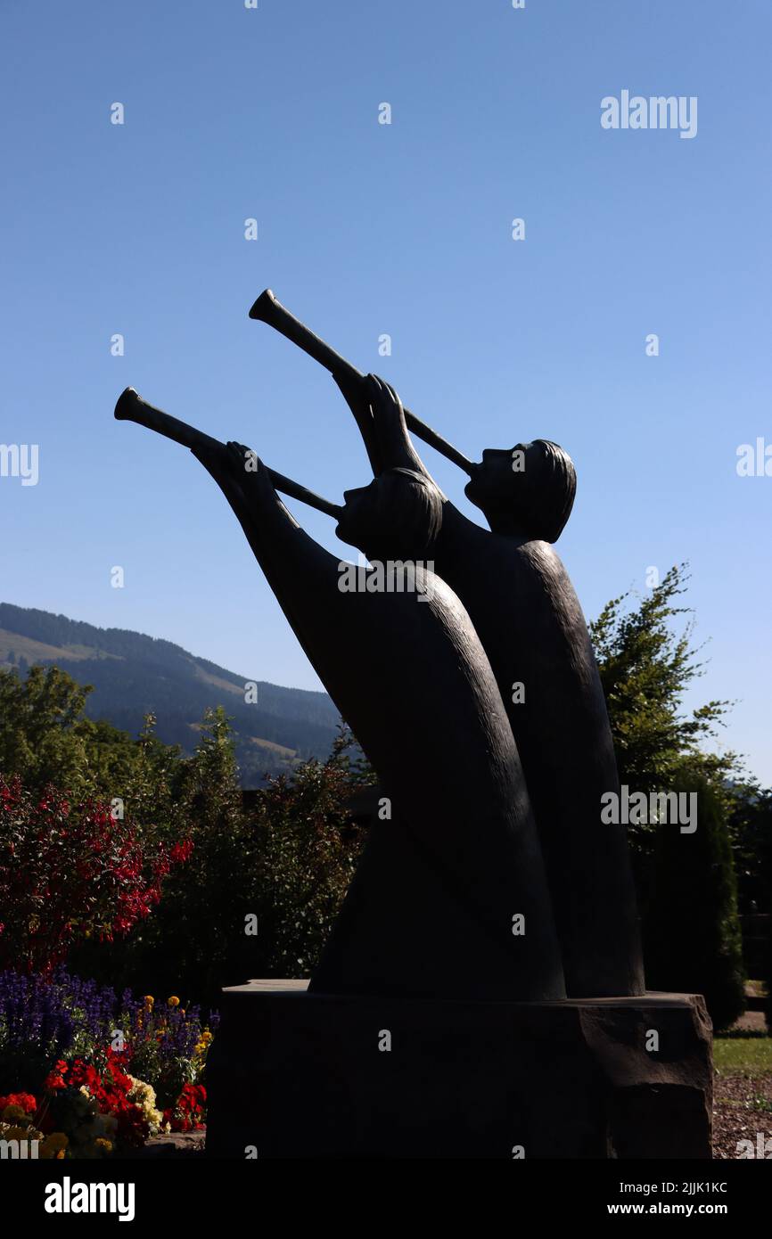 statua con tromba. godetevi le loro trombe durante l'estate con cielo blu e fiori nel giardino pubblico. Foto Stock