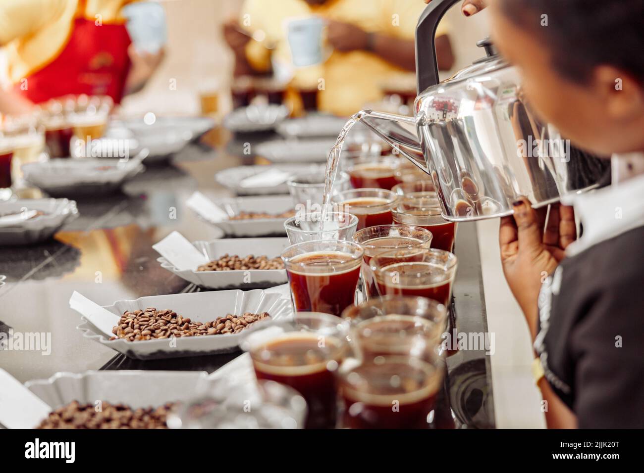 Donna che versa l'acqua dal bollitore per la degustazione del caffè Foto Stock