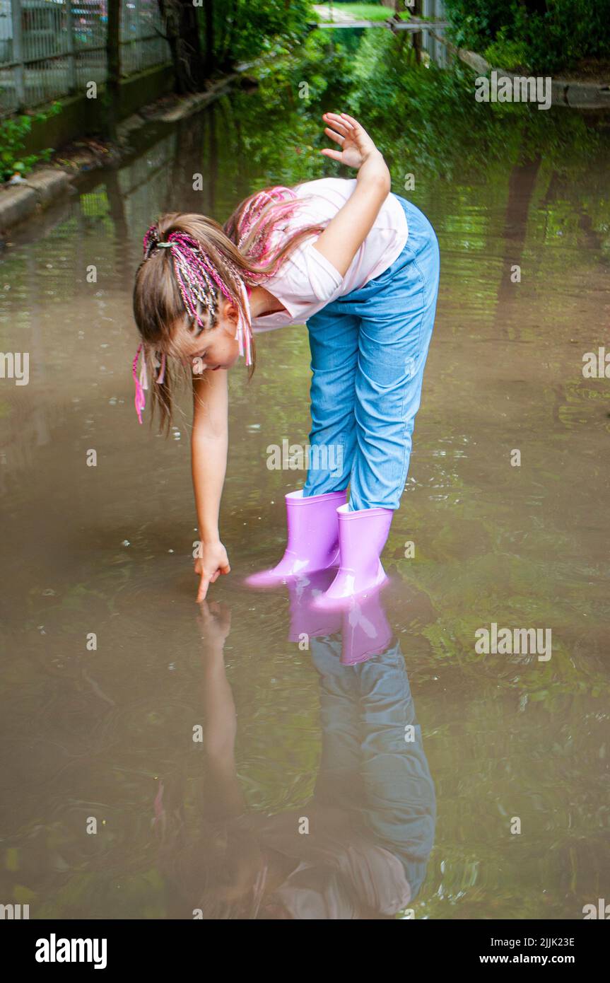 Giovane donna seduta nel giardino di indossare stivali neri con gambe  parted Foto stock - Alamy