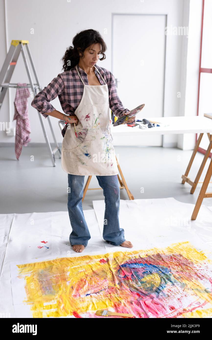 Immagine verticale della pittura biraciale femminile sul pavimento in studio Foto Stock