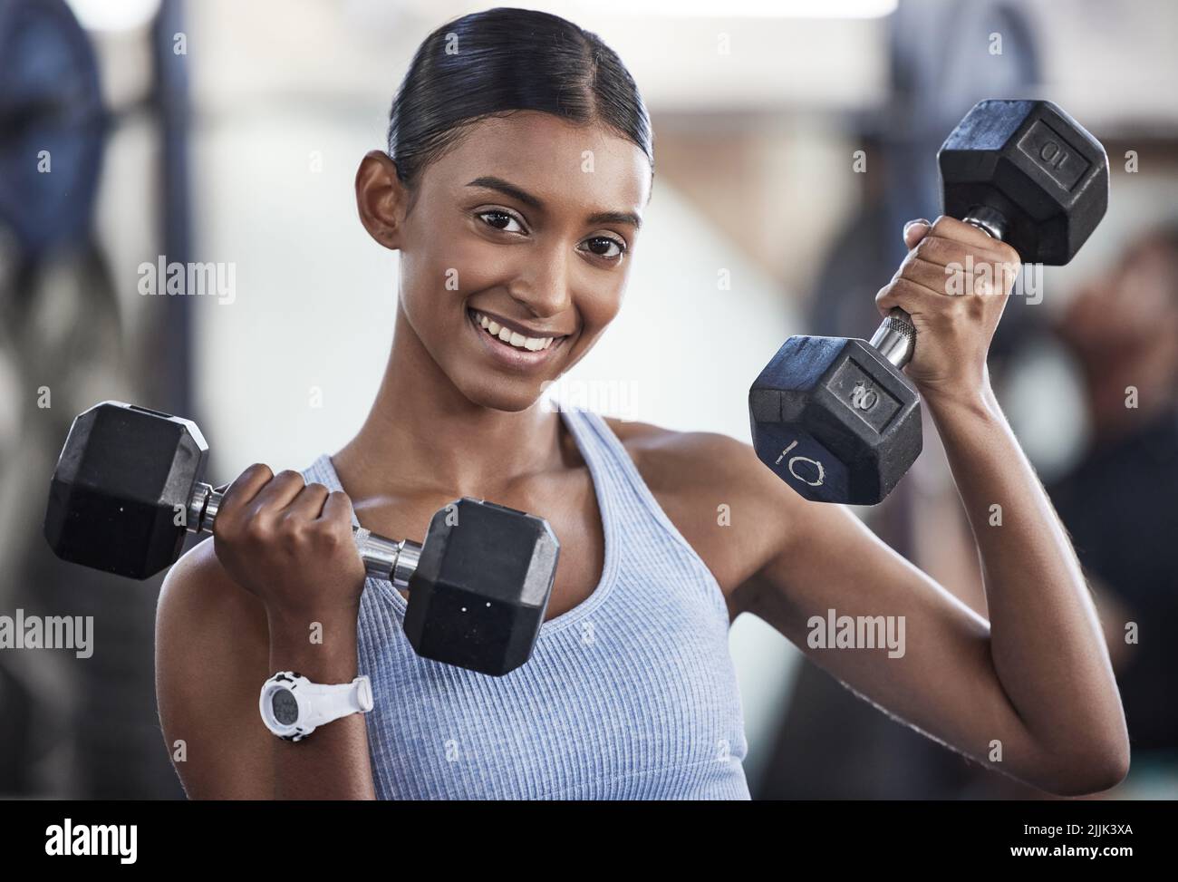 Mi sono trasferito su pesi più pesanti. Ritratto di una giovane donna sportiva che si esercita con manubri in palestra. Foto Stock