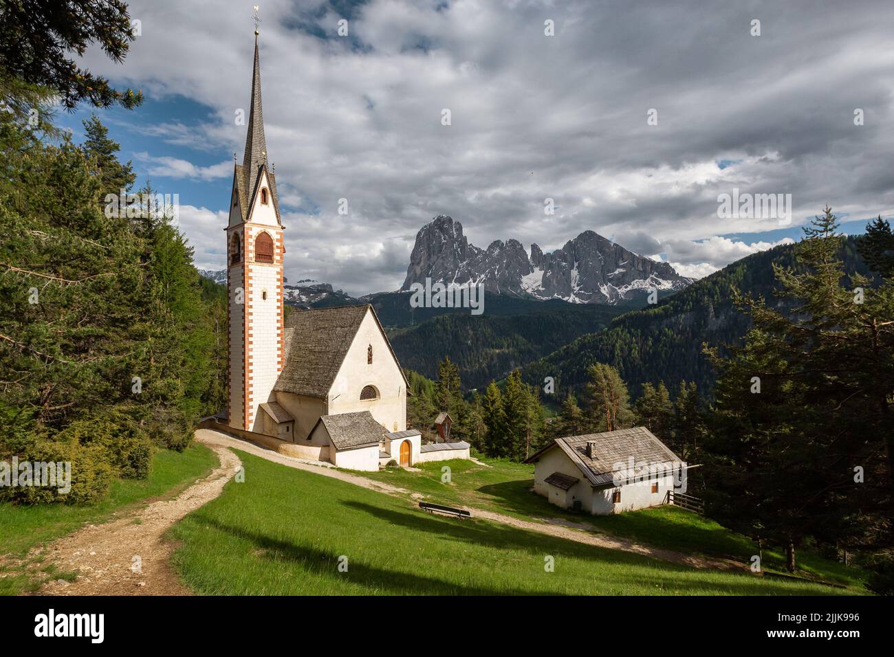 Una vista ipnotica di una chiesa con le colline boscose e la roccia enorme sullo sfondo Foto Stock
