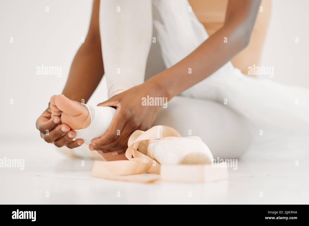 Nessun progresso senza dolore. Una ballerina irriconoscibile che si lega alle sue scarpe pointe. Foto Stock