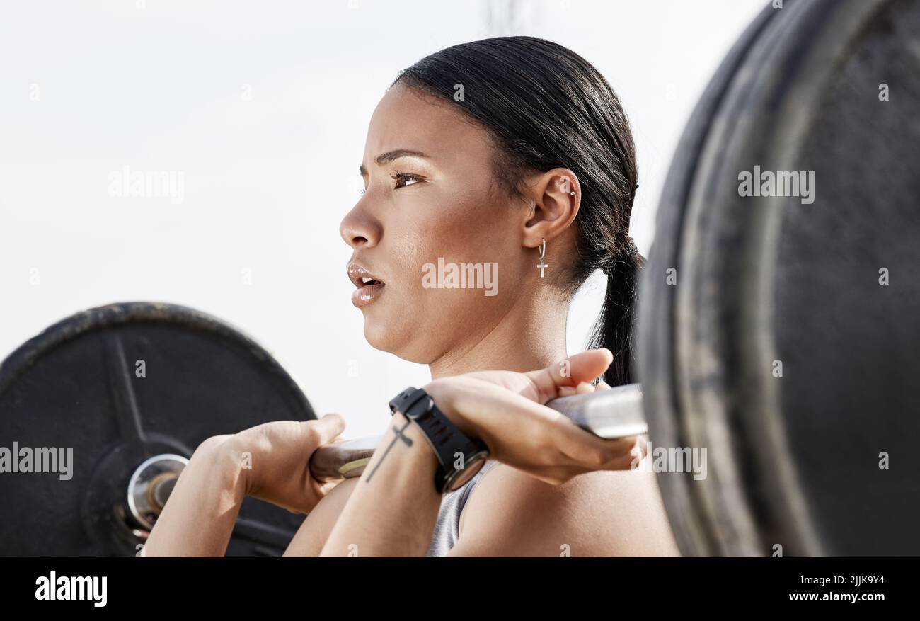 Theres non formula segreta, ho messo nel lavoro. Una giovane donna che usa un barbell mentre si esercita all'aperto. Foto Stock