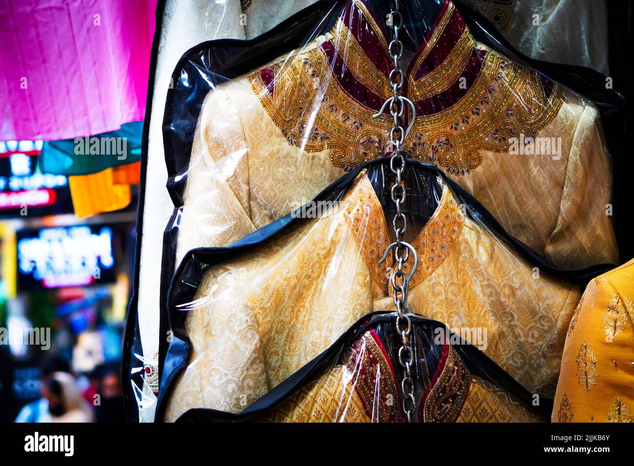 Un primo piano della tradizionale maglia indiana Sherwani appesa su una parete di un mercato su una fiera di strada Foto Stock