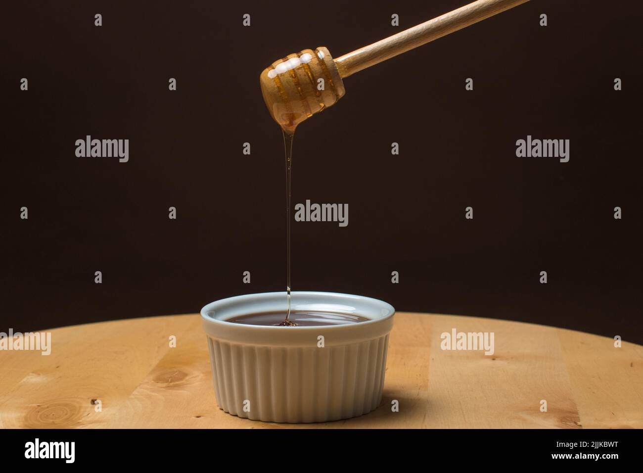 Delizioso miele gocciolante sullo sfondo scuro Foto Stock