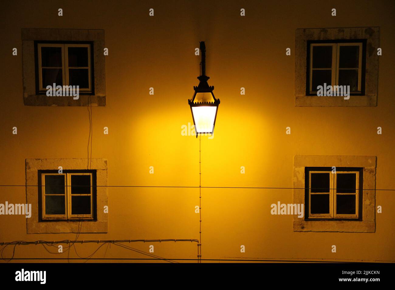 Una lampada luminosa appesa su una parete di un edificio residenziale Foto Stock