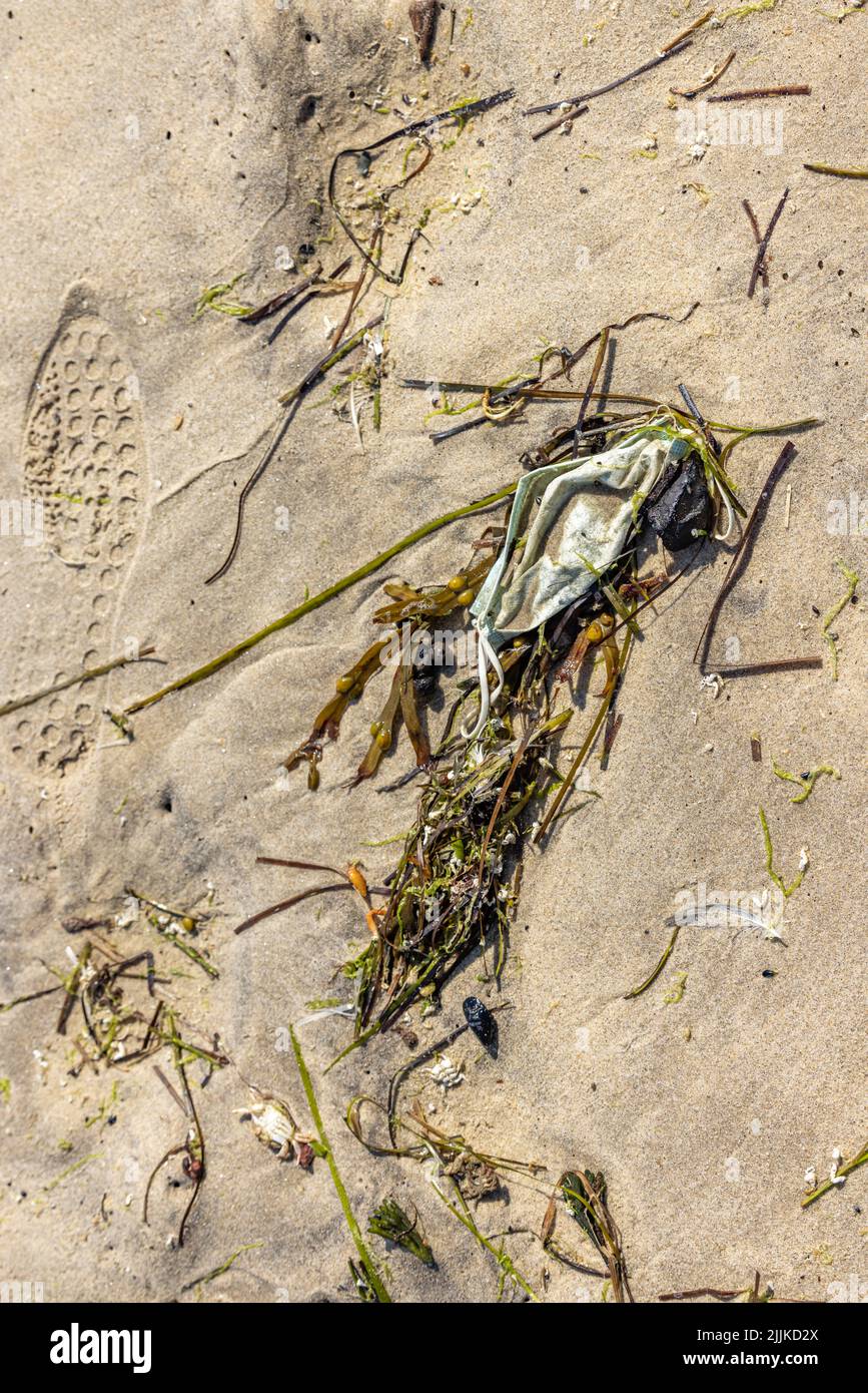 Una maschera medica usata sulla spiaggia Foto Stock