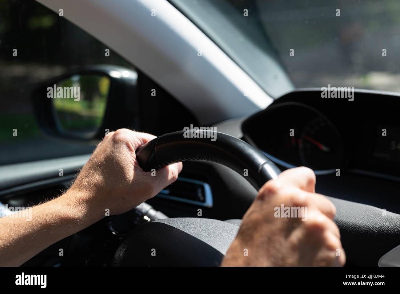 Le mani bianche maschili controllano il volante di un'auto durante la guida su strada. Non ci sono persone o marchi riconoscibili nella foto. Foto Stock