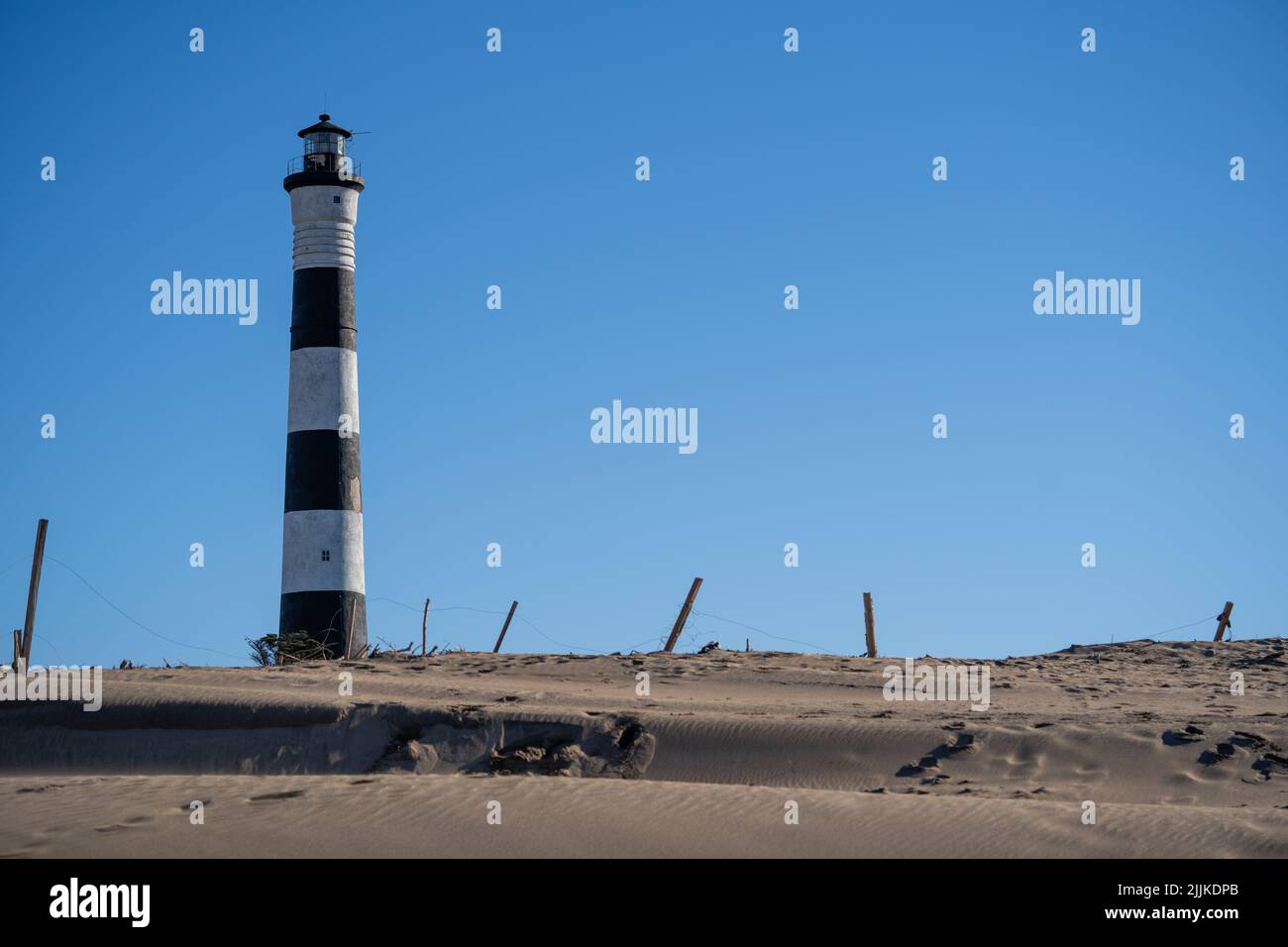 Scatto frontale di un faro sulla spiaggia, una giornata di sole con un cielo limpido Foto Stock