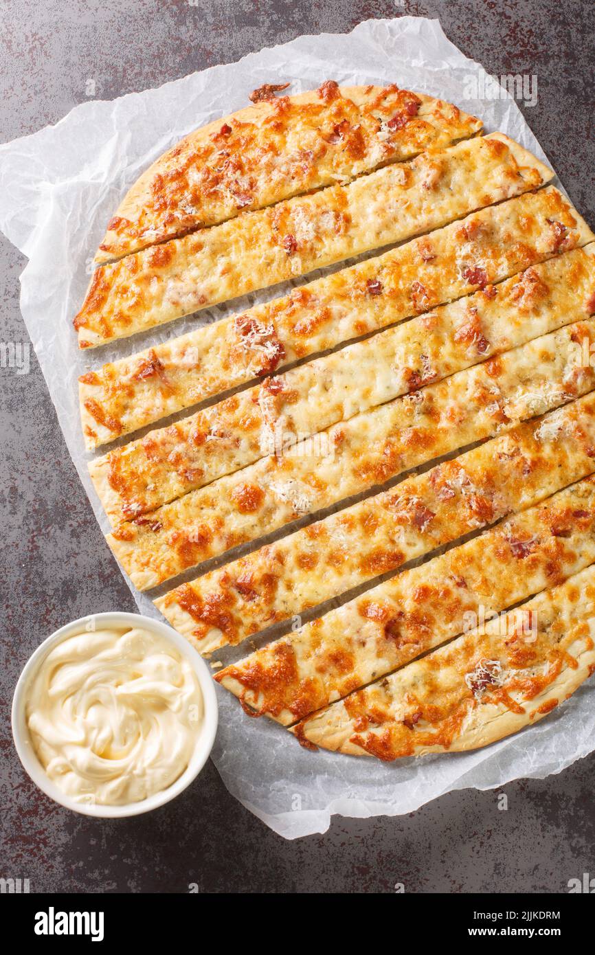 Le dita di formaggio all'aglio sono un piatto canadese dell'Atlantico, simile ad una pizza affettata in strisce sottili spicup nella carta sul tavolo. Vista verticale dall'alto per Foto Stock