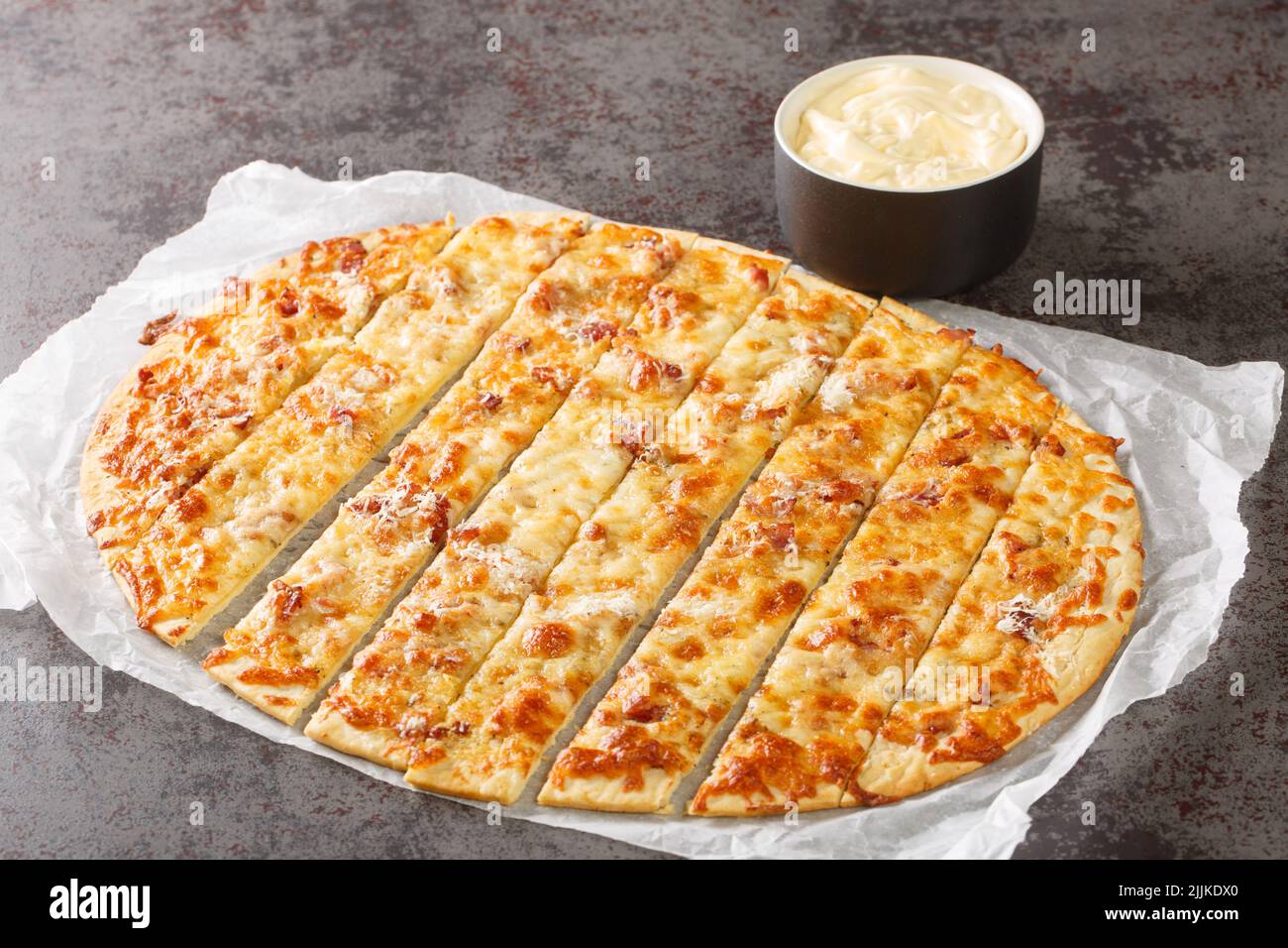 Dita all'aglio fatte in casa con mozzarella, pancetta e burro alle erbe e Donair Sauce primo piano su carta sul tavolo. Orizzontale Foto Stock