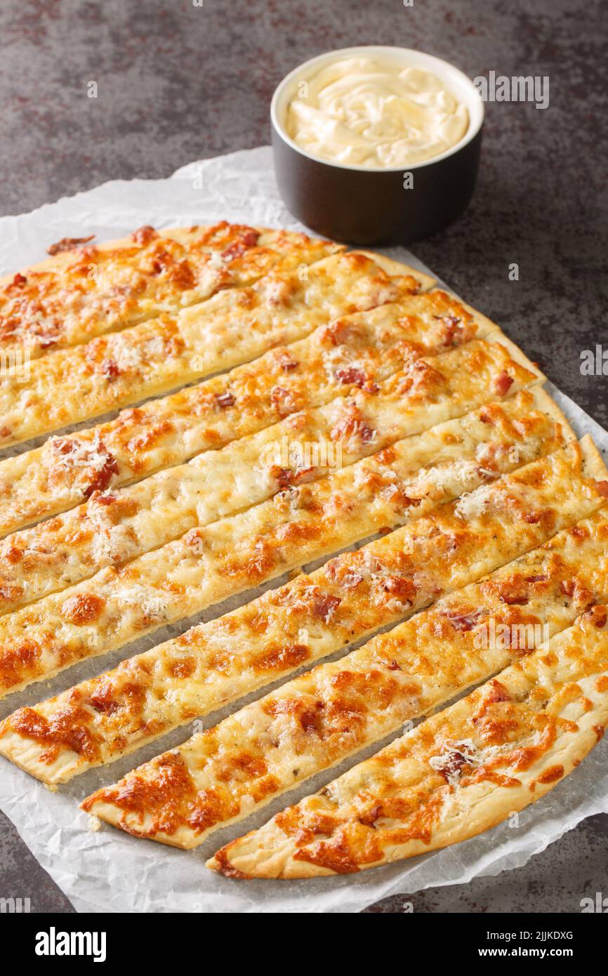 Deliziose dita all'aglio con burro alle erbe e mozzarella fusa spicchio di formaggio sulla carta sul tavolo. Verticale Foto Stock