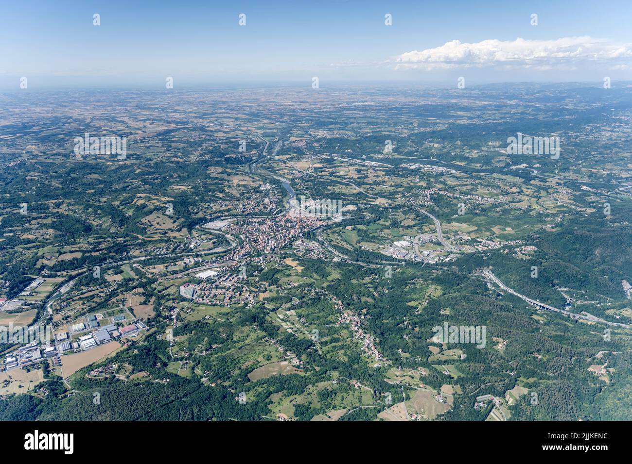 Scatto aereo, da un piccolo aereo, della cittadina di Ovada vicino all'autostrada A36 a Monferrato con le pianure della Padania sullo sfondo, girato da sud ovest in luminoso Foto Stock